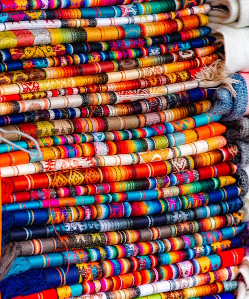 Stack of different vibrant cloth materials with diff weaves.