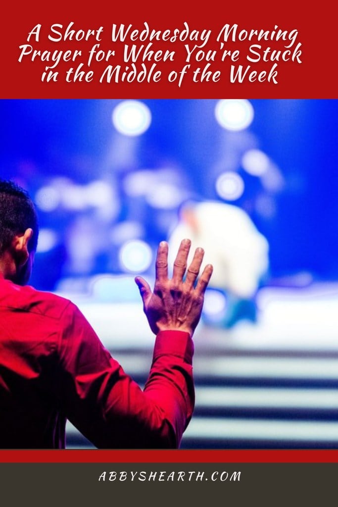 Man in red shirt with hands raised in prayer.