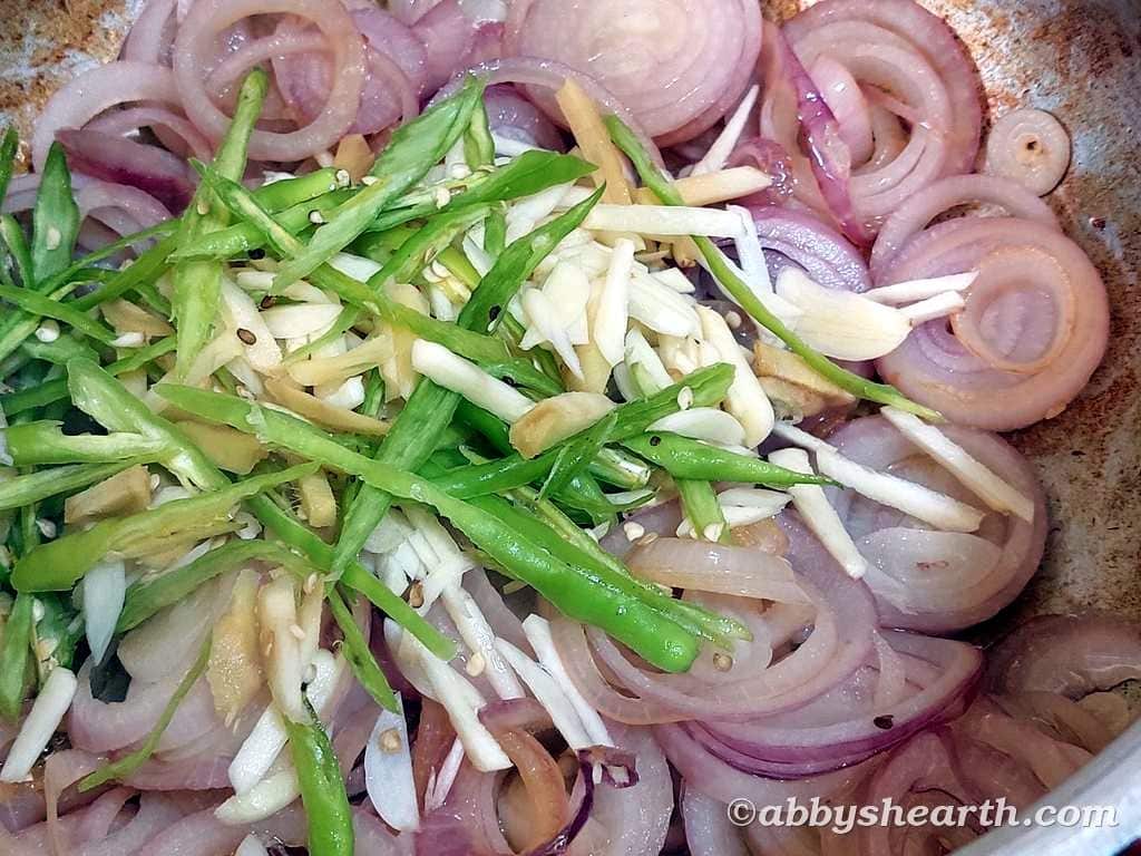 Add the sliced garlic chilies and ginger to the onions.