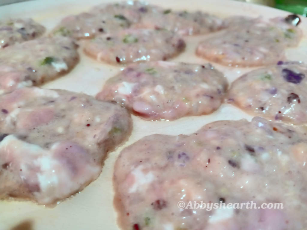 Spoonfuls of brain batter in cutlet sizes in a pan.