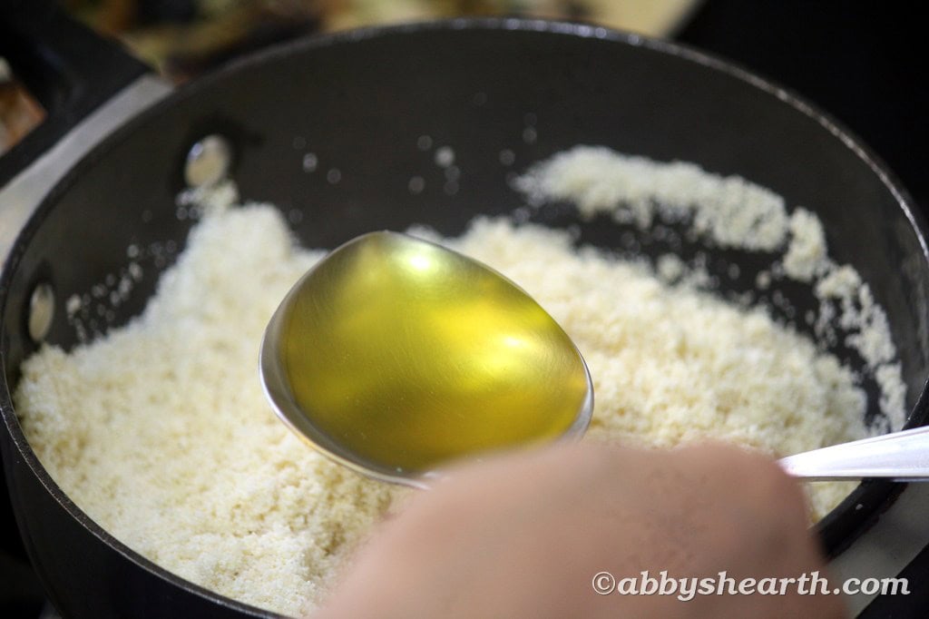 Adding ghee to the fried semolina.