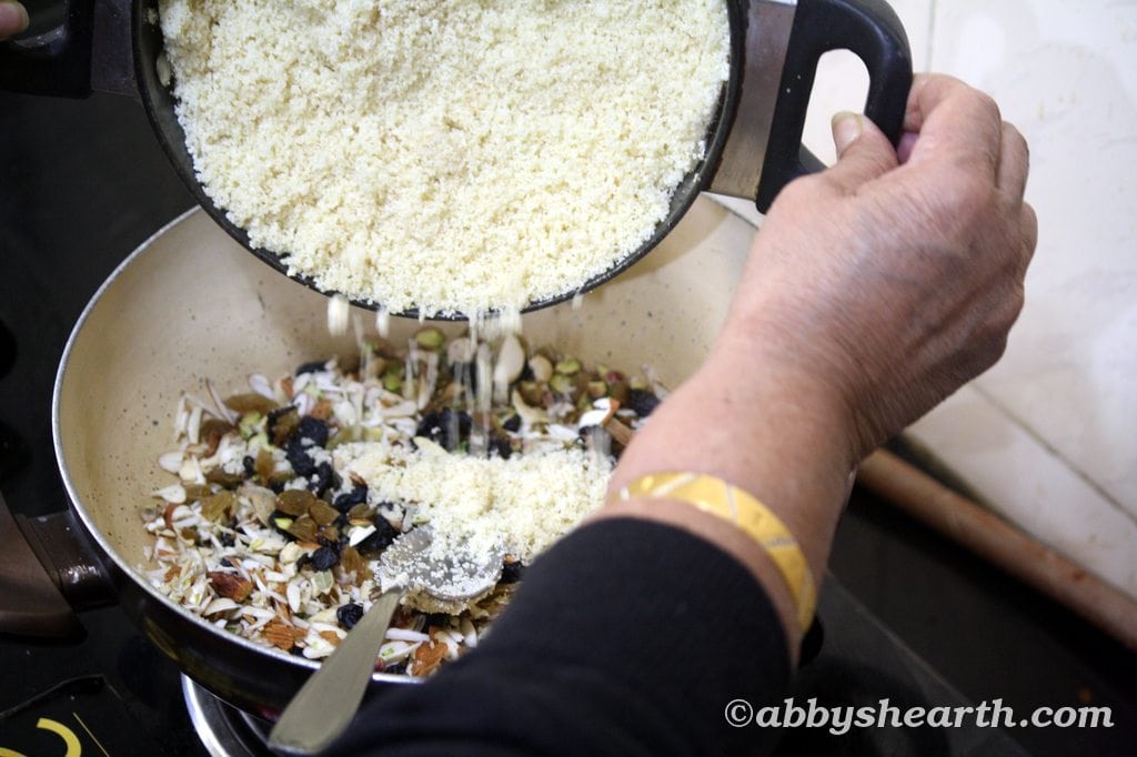 Mom adds the fried sojee to the toasted nuts.