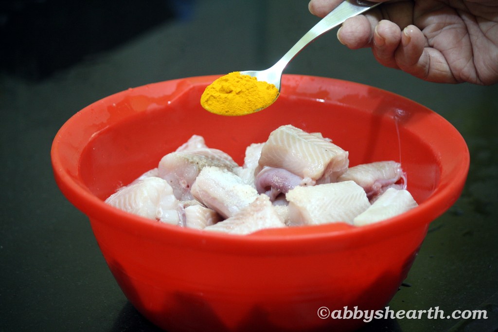 Adding turmeric powder to milk shark pieces.
