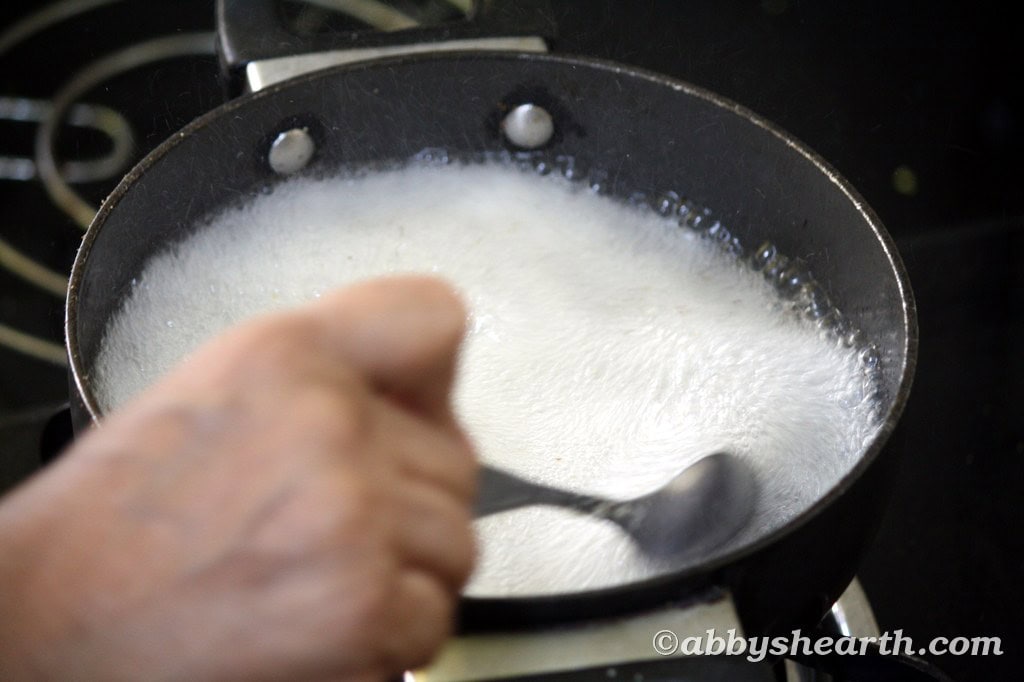 Cooking semolina halwa with sugar and nuts in a pan for Sojee Halwa recipe.