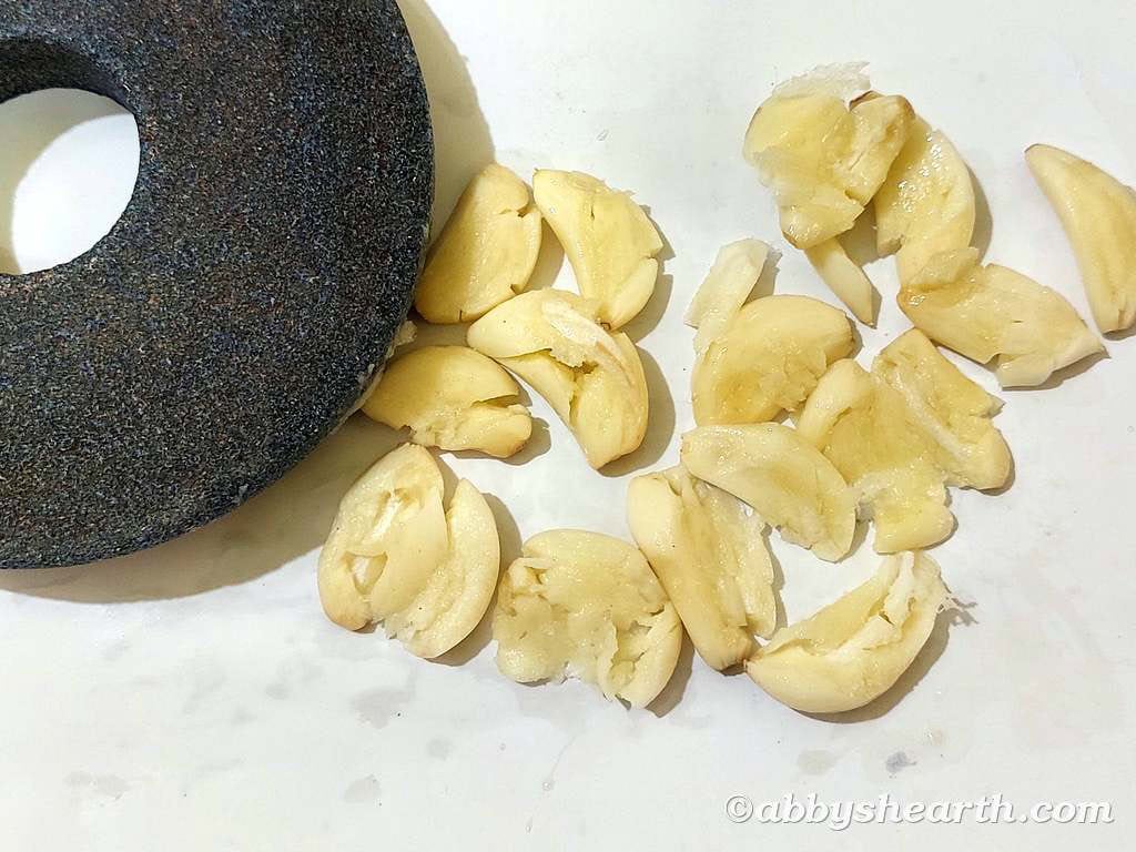 Fresh garlic cloves next to a grinding mortar.