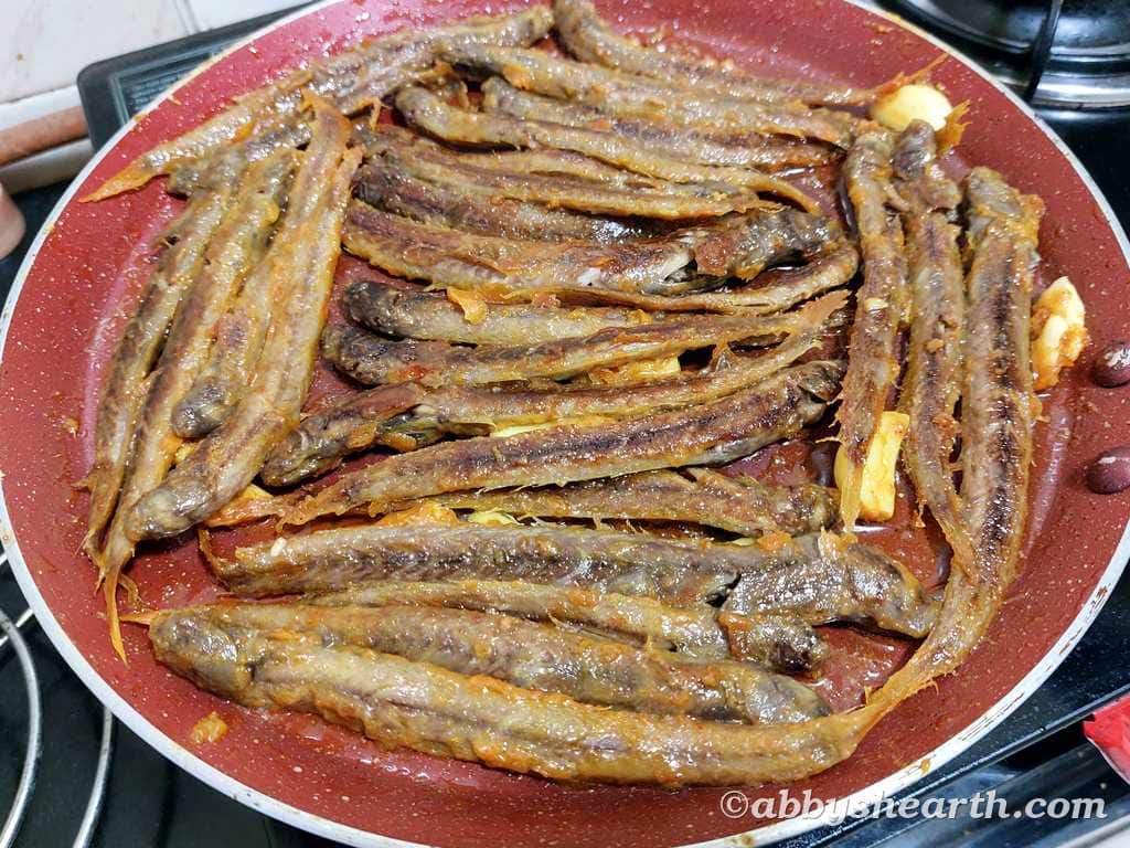 Crispy fried fish called kalentas in a red skillet, ready to serve.