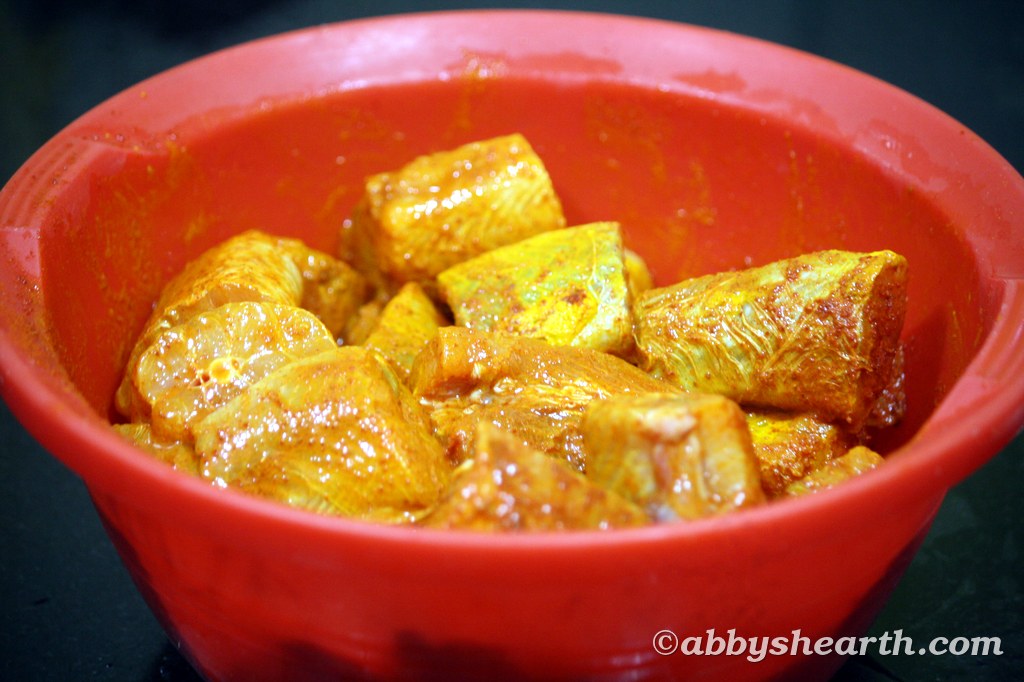 Raw mushi aka milk shark fish pieces in a red bowl with spices.