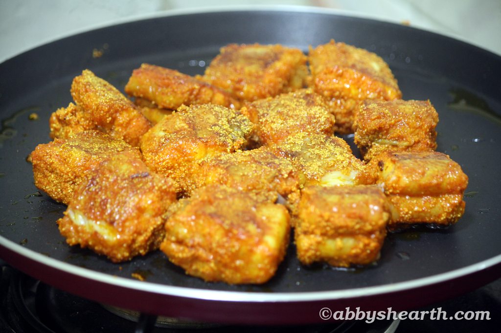 Crispy fried shark fish pieces on a black skillet, golden and seasoned for flavor.