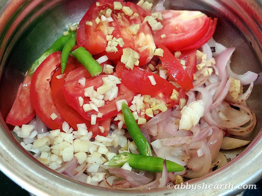 Chopped tomatoes, onions, garlic, and green chilies in a cooking pot for Chicken Liver Stir-Fy.