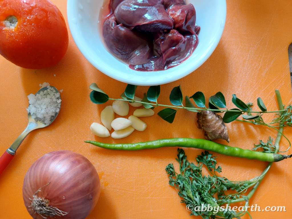 Fresh chicken liver, garlic, ginger, chili, onion, ginger, garlic on a chopping board.