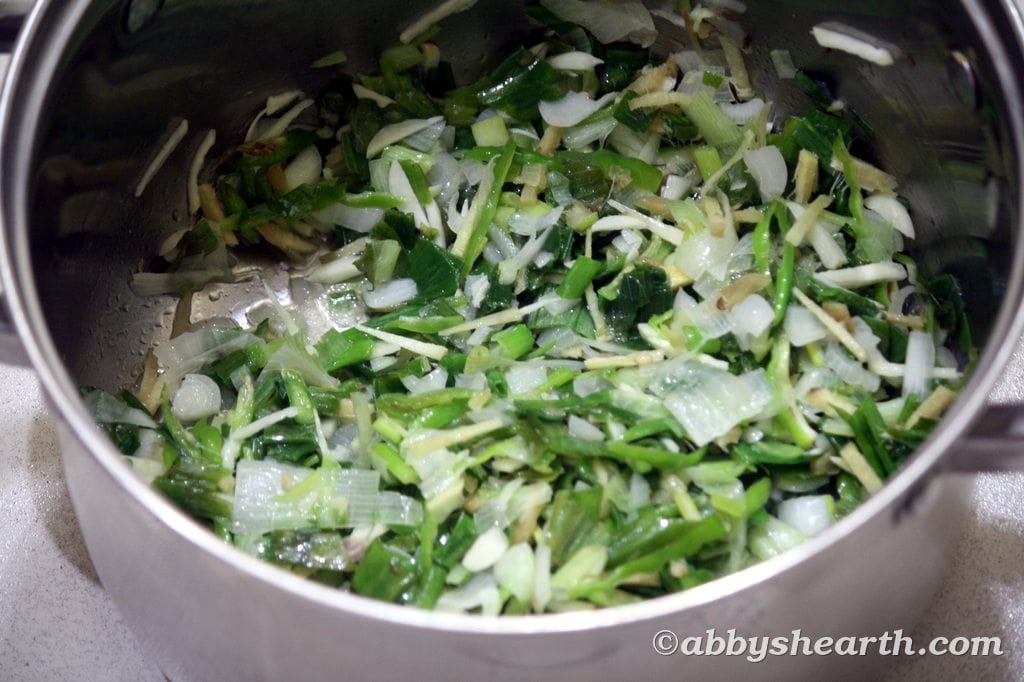 Ginger, garlic and chilli slivers cooking with spring onions.