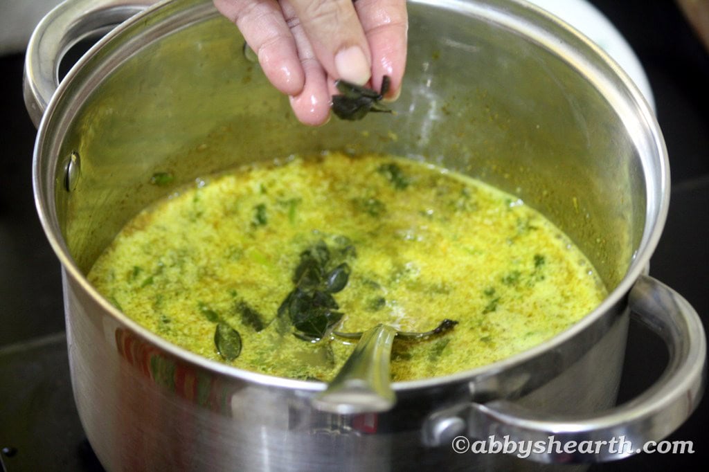Hand adding curry leaves to the pot.