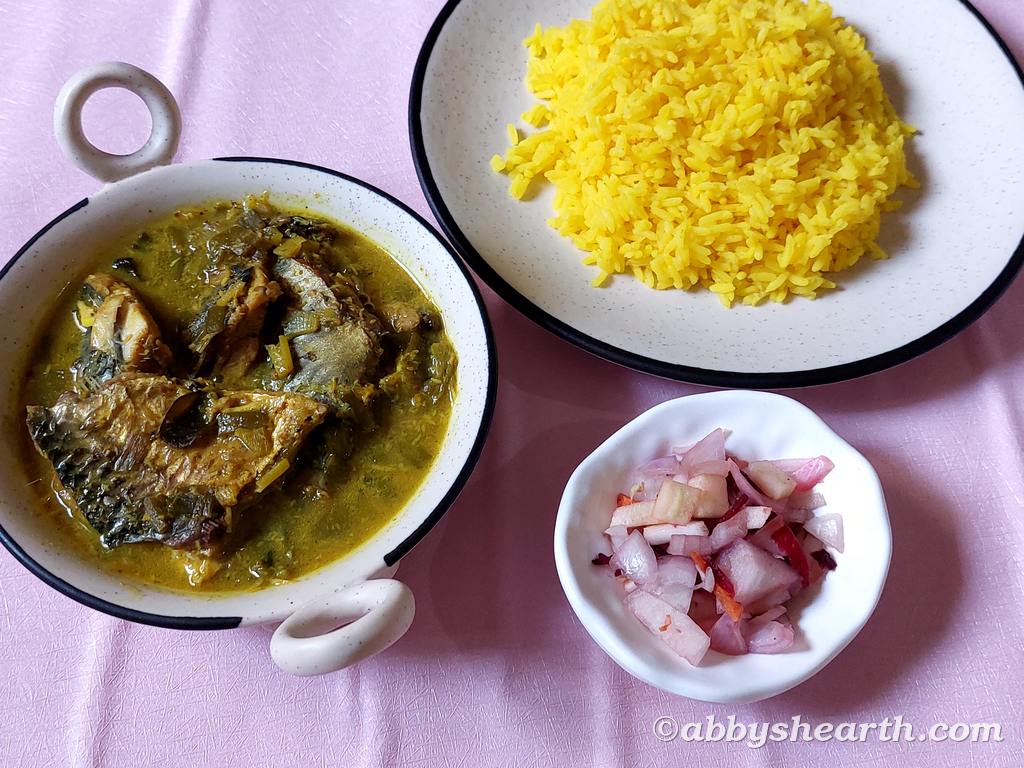 Dishes of hilsa khujit curry, turmeric rice and salad.
