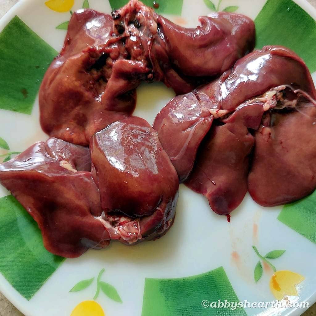 Fresh chicken livers on a decorative plate, ready for cooking.