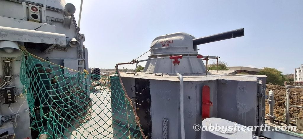 Close-up of a military shipboard gun with netting and equipment in Diu, India.