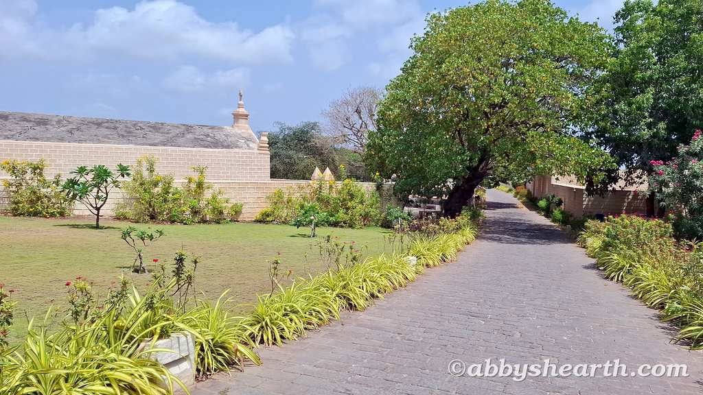 Peaceful garden path with lush greenery and a church in Diu.