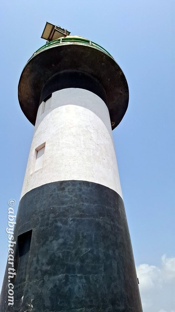 Tall Diu lighthouse against blue sky, iconic maritime landmark.