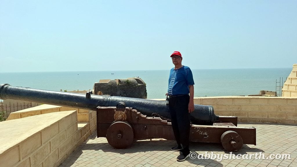 Senior citizen standing near historic cannon overlooking the sea in Diu Fort.