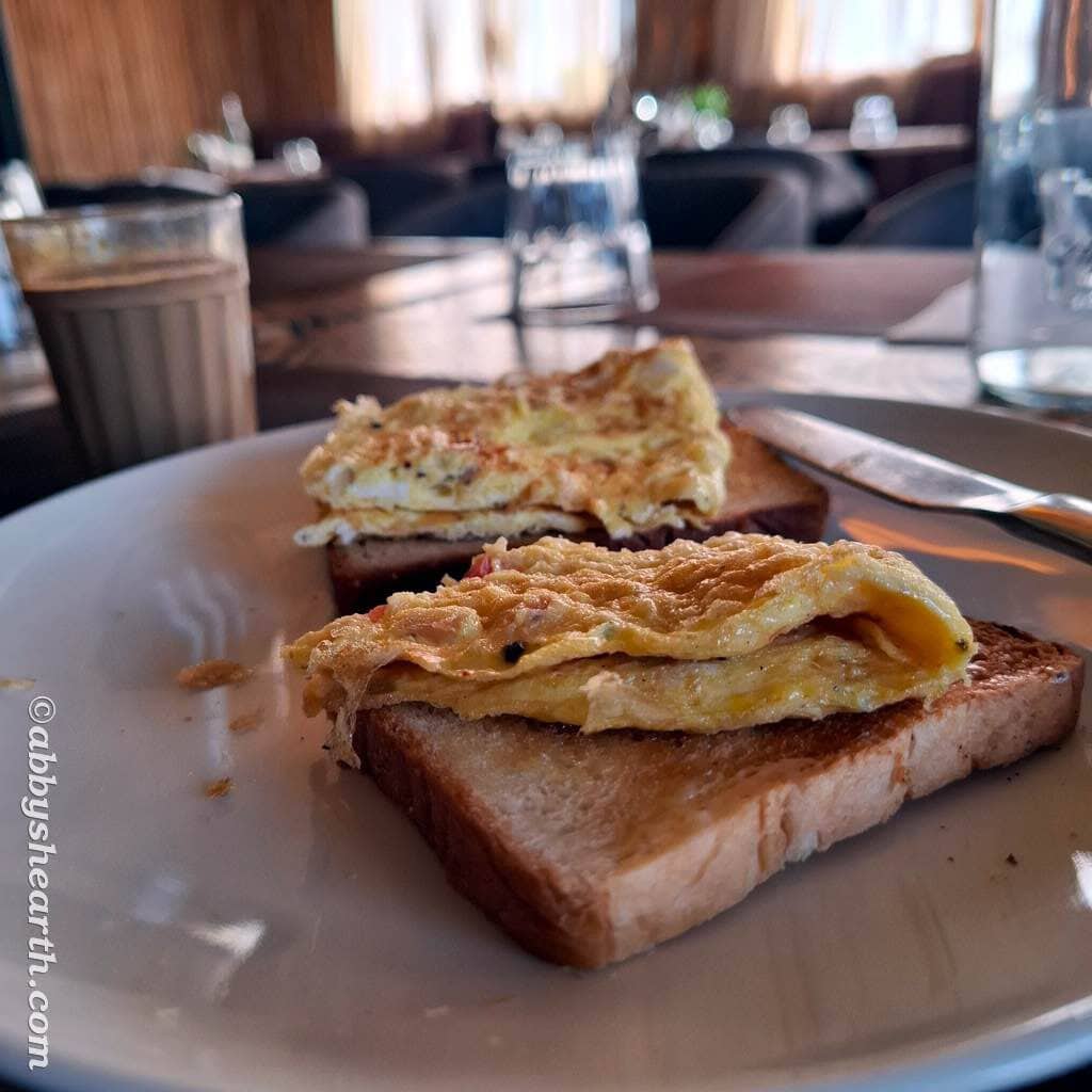 Close-up of toast with omelette on top, in a cozy restaurant setting.