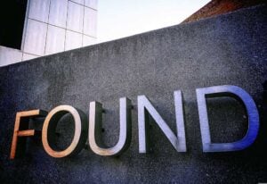 Close-up of a sign with the word 'FOUND' on a dark wall.