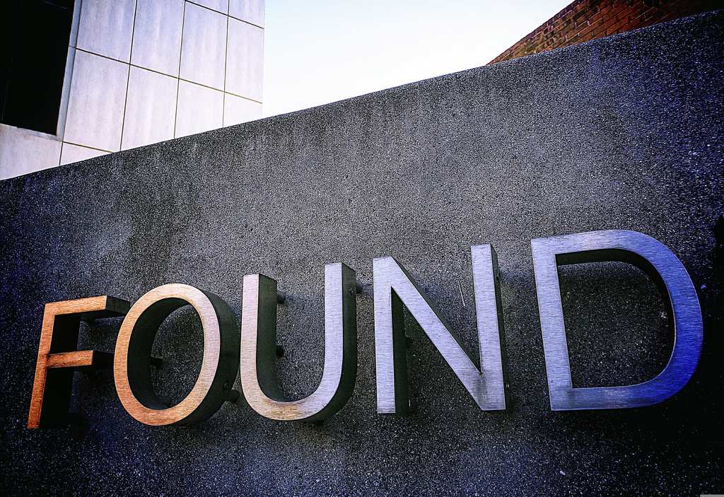 Close-up of a sign with the word 'FOUND' on a dark wall.