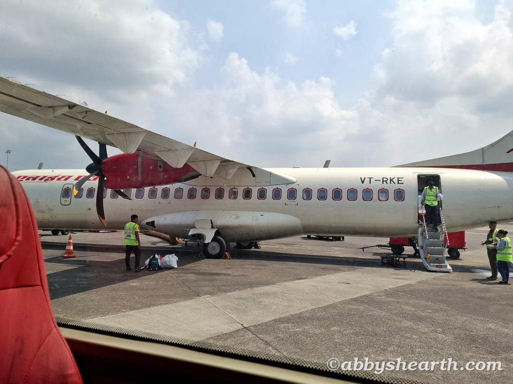 Passengers boarding a small aircraft at an airport tarmac with ground crew assistance.