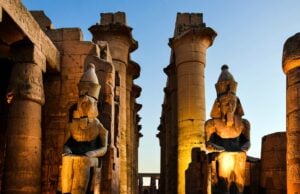 Sunlit ancient Egyptian statues and columns at sunset in Luxor.